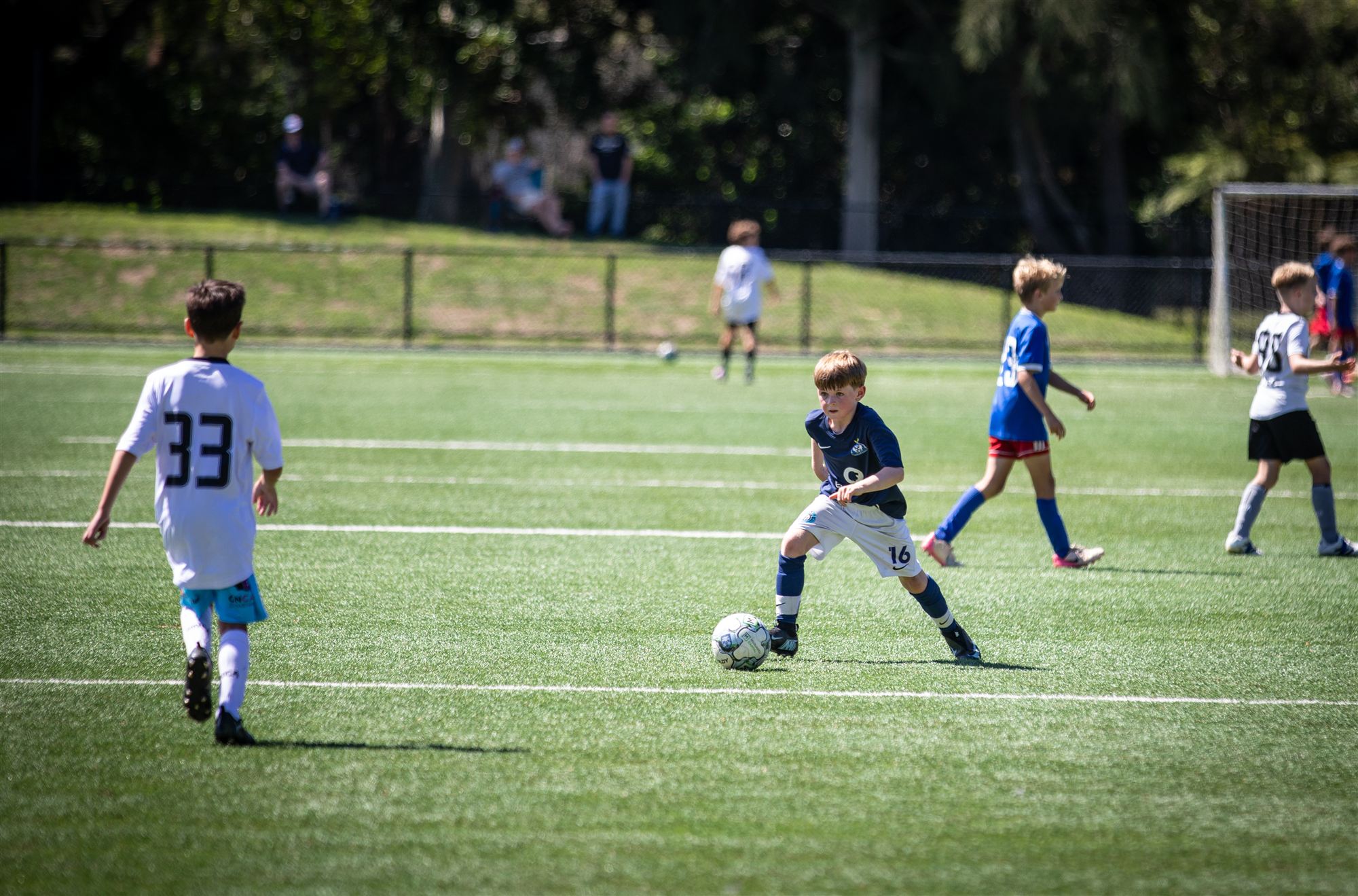 Midfielder shielding the ball from an onrushing defender